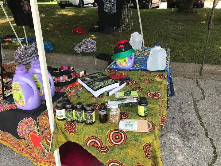 A vendor table of oils and goods on a colorful cloth.