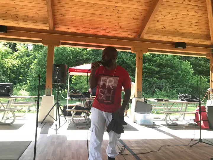 A man in red performing under the shelter.