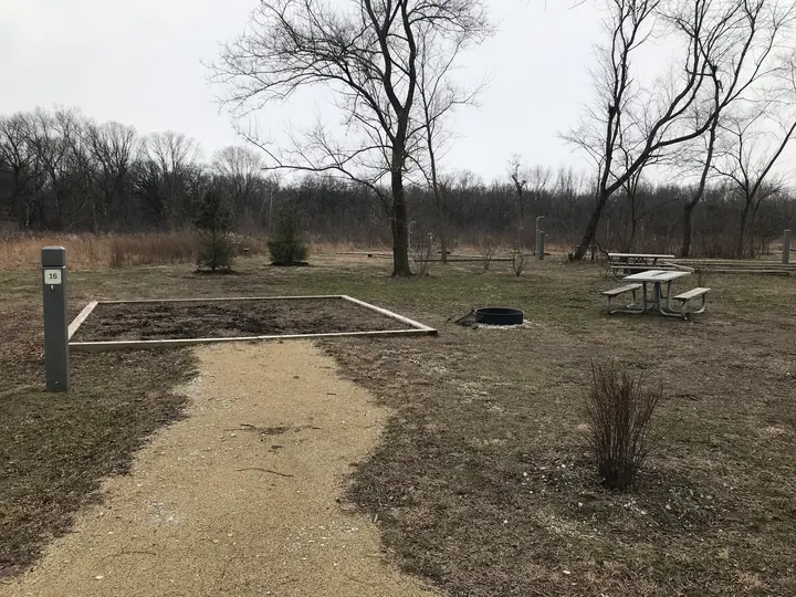 A gravel path leading to a campsite with a fire pit.