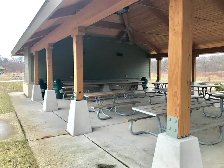 A picnic shelter with wooden posts and tables.