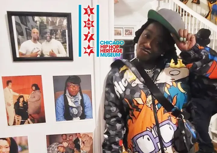 A visitor in a printed jacket posing next to framed photos.