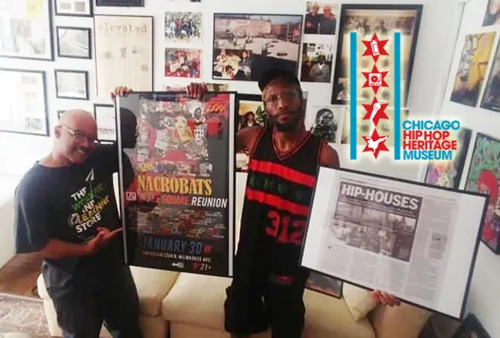 Two men holding up framed posters in the museum.
