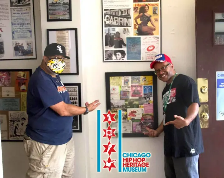 Two men pointing at photos on the wall.